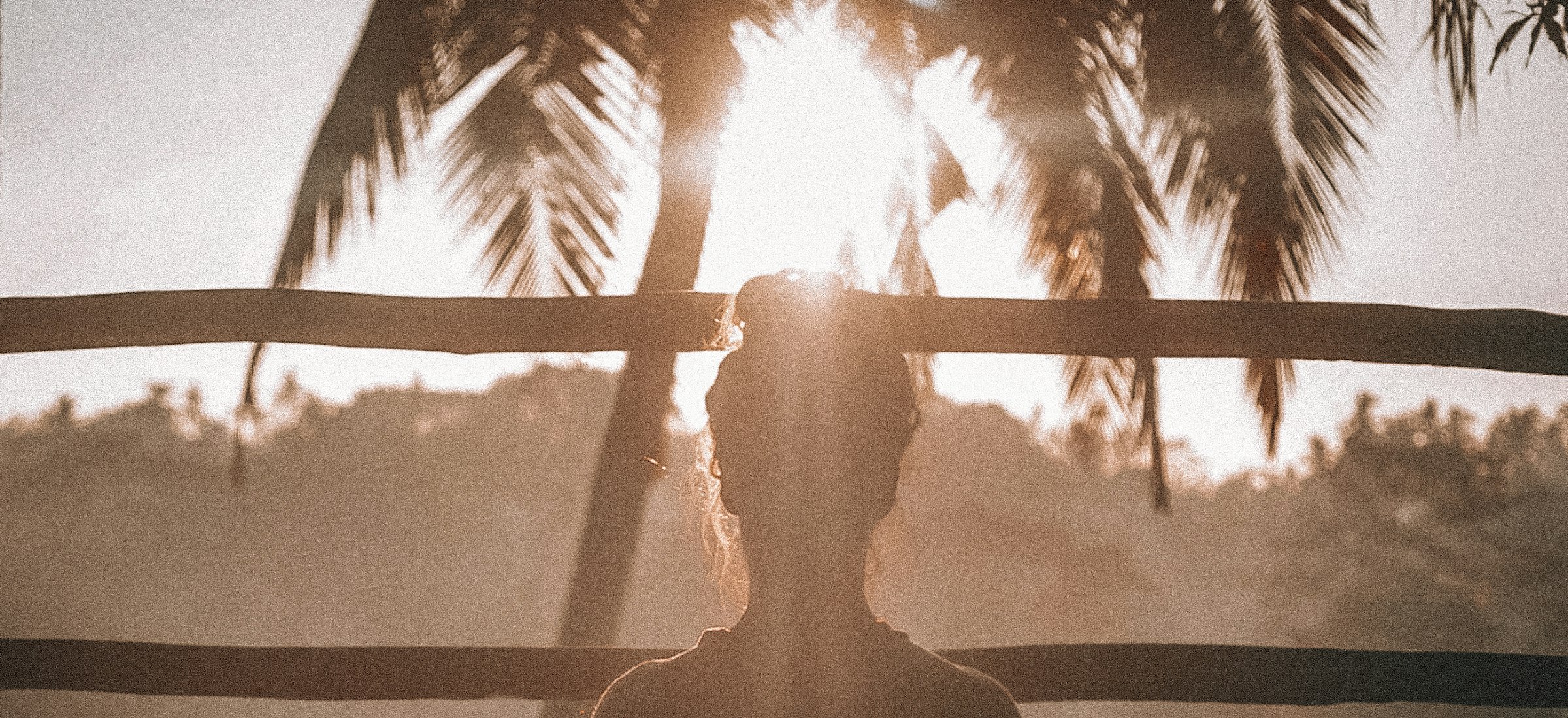 A woman meditating at sunrise on a wooden deck